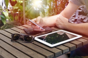 Person Using Phone While Leaning on Wooden Table Outdoor