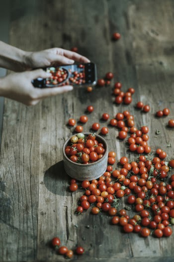 Person Using Smartphone Taking Photo of Cherry Tomatoes on Container