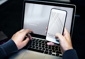 Person Using Smartphone While Facing Laptop Computer
