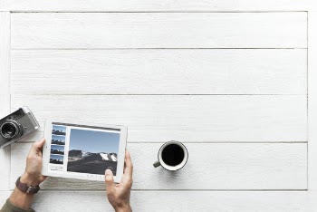 Person Using Tablet Computer Near Mug and Camera