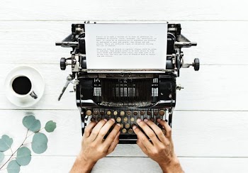 person using typewriter near white ceramic cup filled with coffee