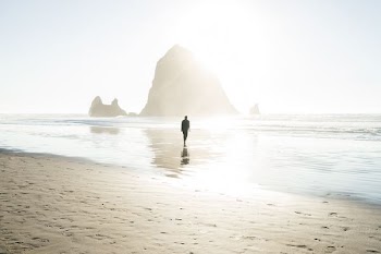 person walking at beach across island during daytime