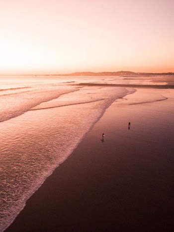 person walking beside beach during daytime
