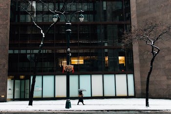 person walking beside building while holding umbrella