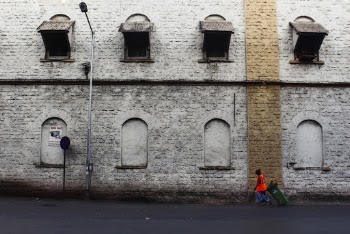 Person Walking by the Sidewalk Near Wall