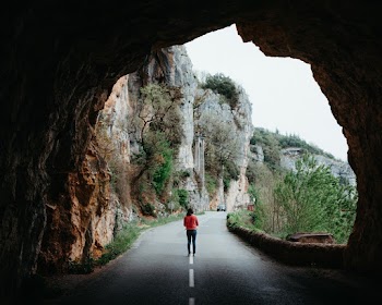 Person Walking in Middle of the Road Under Tunnel