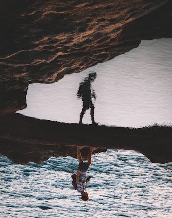 person walking near body of water mirror photography