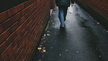 person walking on black-paved alley