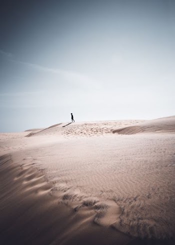 person walking on dune desert during daytime