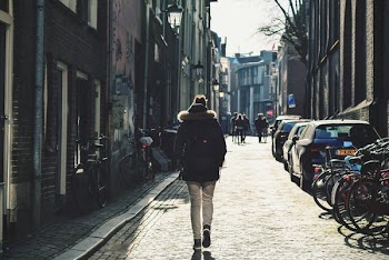 Person Walking on Street Near Parked Bike and Cars