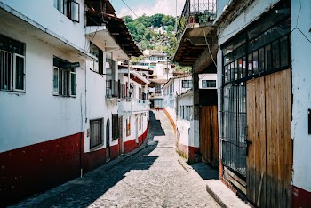 Person Walking Through an Alley in the Middle of White Buildings