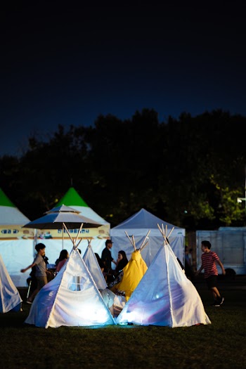 Person Walking White Camping Huts at Night
