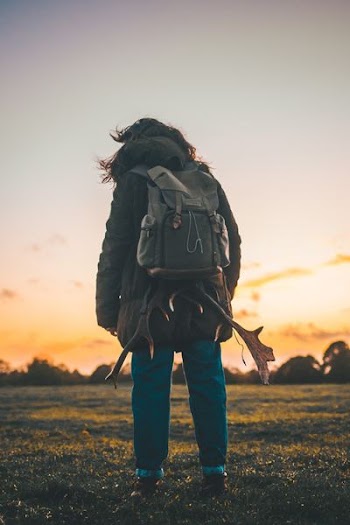 person wearing backpack standing on grass field