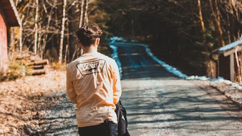 Person Wearing Beige Vans Long-sleeved Shirt Near House