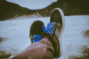 Person Wearing Black and Brown Shoes in Front of Body of Water