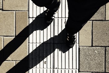 Person Wearing Black and White Shoes Walking on Street during Day