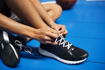Person Wearing Black-and-white Sneakers Tying Shoelaces