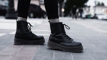person wearing black boots standing on gray concrete floor