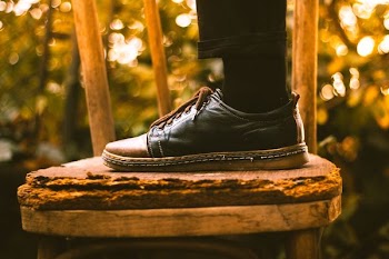person wearing black dress shoe stepping on chair