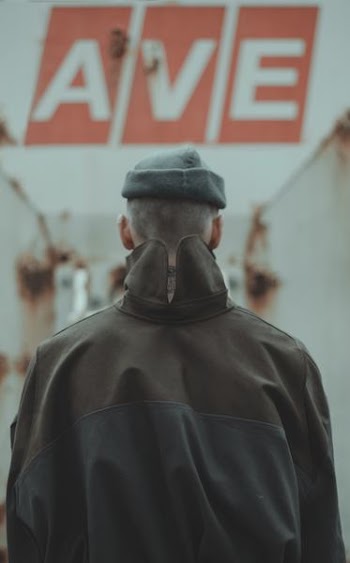 person wearing black jacket in front of ave signage