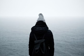 person wearing black jacket standing in front of the ocean