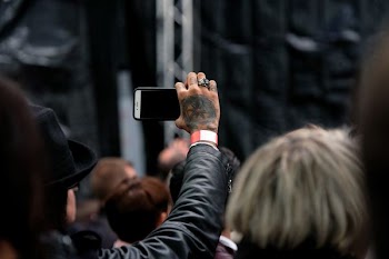 person wearing black jacket using white phone