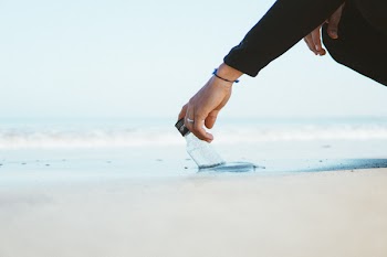 Person Wearing Black Long-sleeved Top Holding Bottle in Ocean