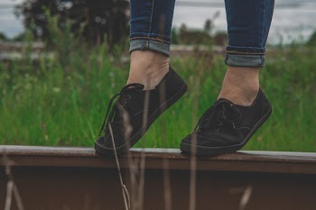 Person Wearing Black Low-top Sneakers Standing on Railing