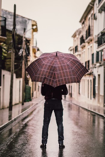 Person Wearing Black Pants Holding Umbrella Standing On Road 