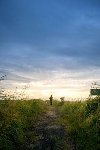 Person Wearing Black Shirt Walking Near Grass Field
