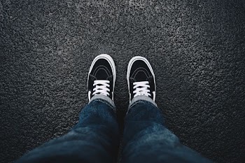 person wearing black sneakers standing on black surface