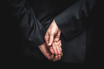 person wearing black tuxedo holding hands behind back