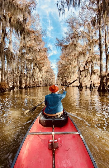 Person Wearing Blue Denim Jacket Riding Red Canoe Boat