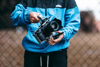 Person Wearing Blue Jacket Standing While Holding Black Camera