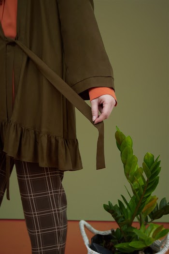 Person Wearing Brown and Orange Long-sleeved Blouse Standing Beside An Indoor Plant