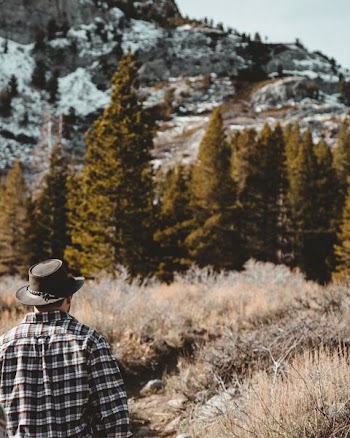 person wearing brown hat standing on forest during day time