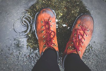 person wearing brown lace-up boots standing on wet ground