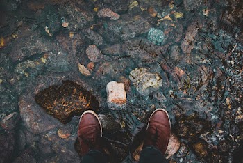 Person Wearing Brown Leather Shoes Standing on Rocky Ground
