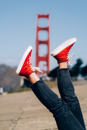 Person Wearing Denim Jeans and Red High-top Sneakers With Feet Up