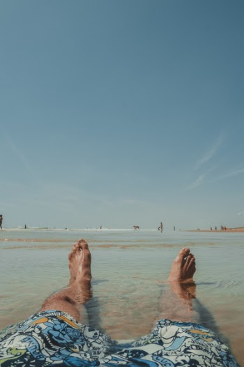 Person Wearing Doodled Boardshorts Sitting on Surface With Water