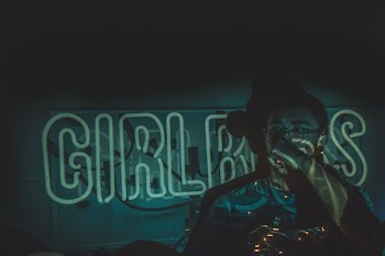 person wearing eyeglasses on green neon signage in dark room