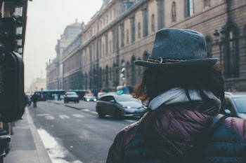 Person Wearing Fedora Hat Walking on Street Near Vehicles