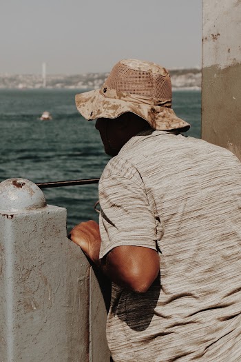 Person Wearing Gray and Brown Hat Near Body of Water