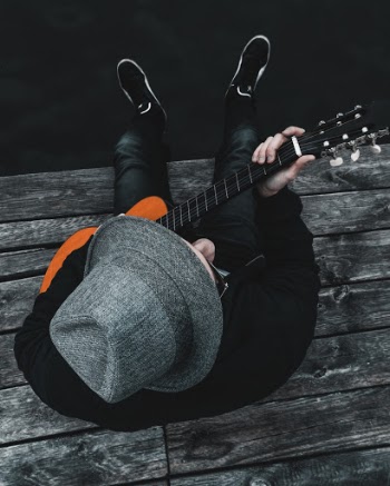 Person Wearing Gray Fedora Hat Playing Acoustic Guitar
