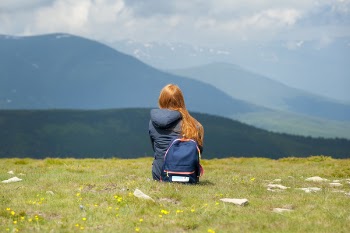 Person Wearing Gray Hooded Jacket Sitting on Grassy Field