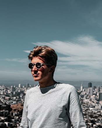 Person Wearing Gray Long-sleeved Shirt Across City Buildings