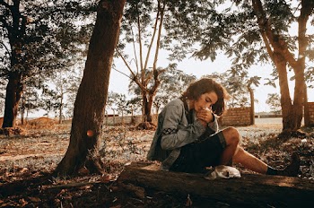 Person Wearing Gray Sweater Sitting on Wood Log