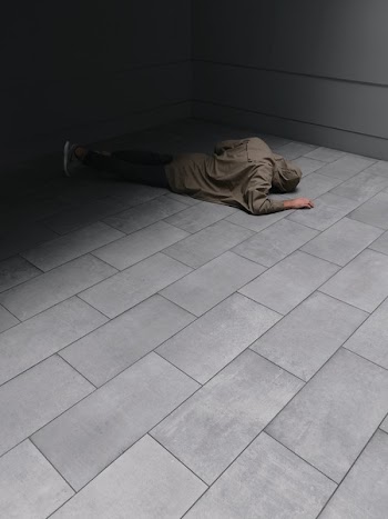 Person Wearing Grey Hoodie and Black Jeans Laying on Floor