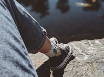 Person Wearing Grey Pants Sitting on Rock