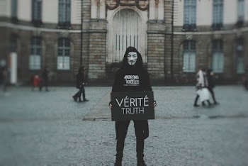 Person Wearing Guy Fawkes Mask Holding Board